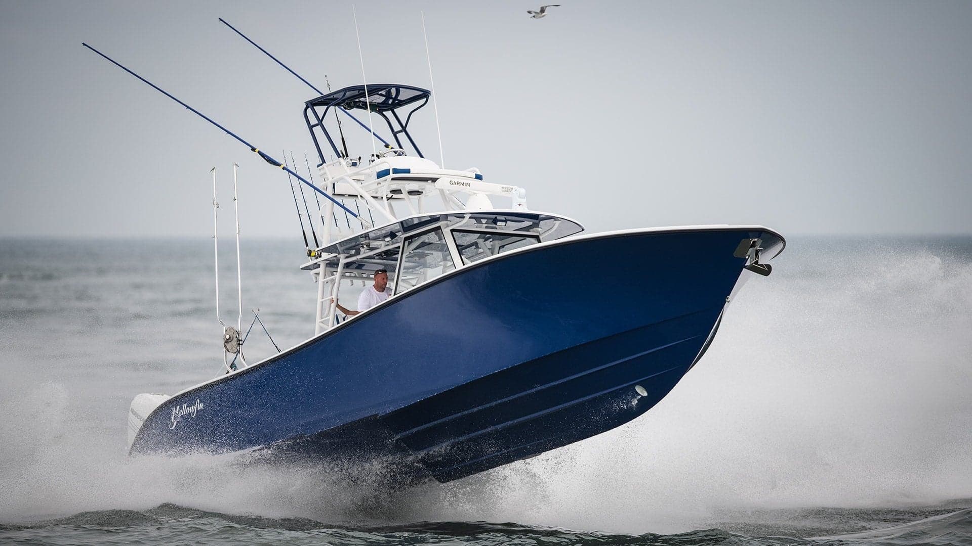 Dark blue Yellowfin center console launching off a wave, photographed by AH360