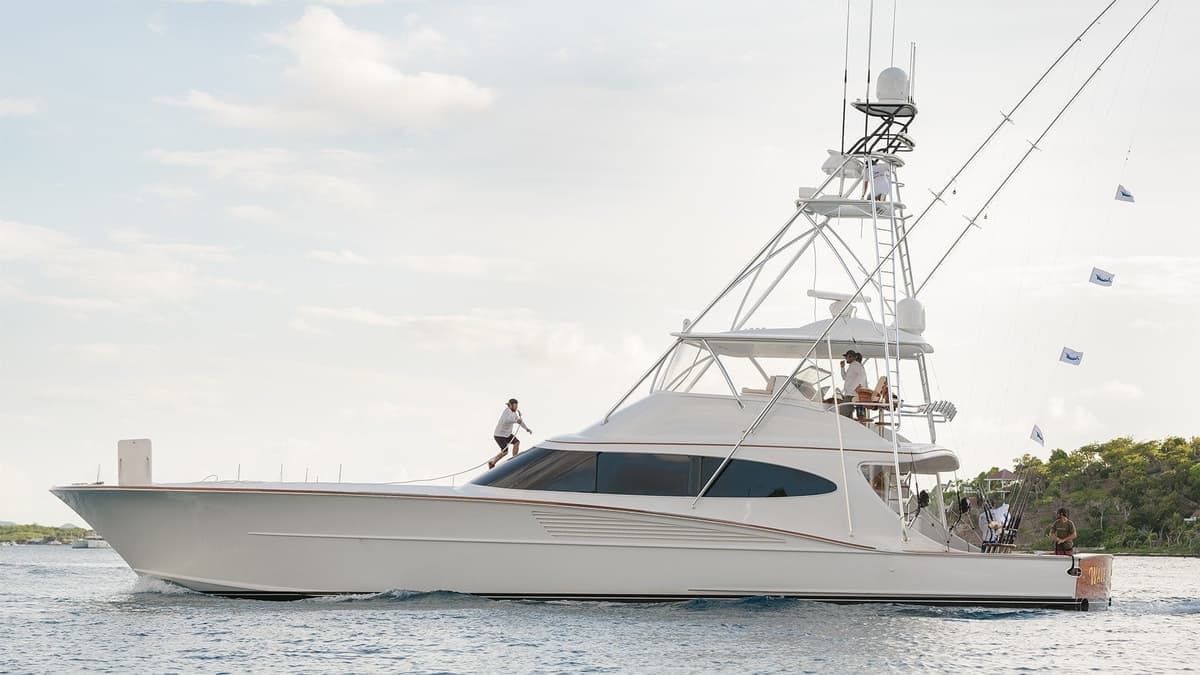 A luxurious sportfishing yacht cruising through calm waters near lush green hills under a dramatic sky