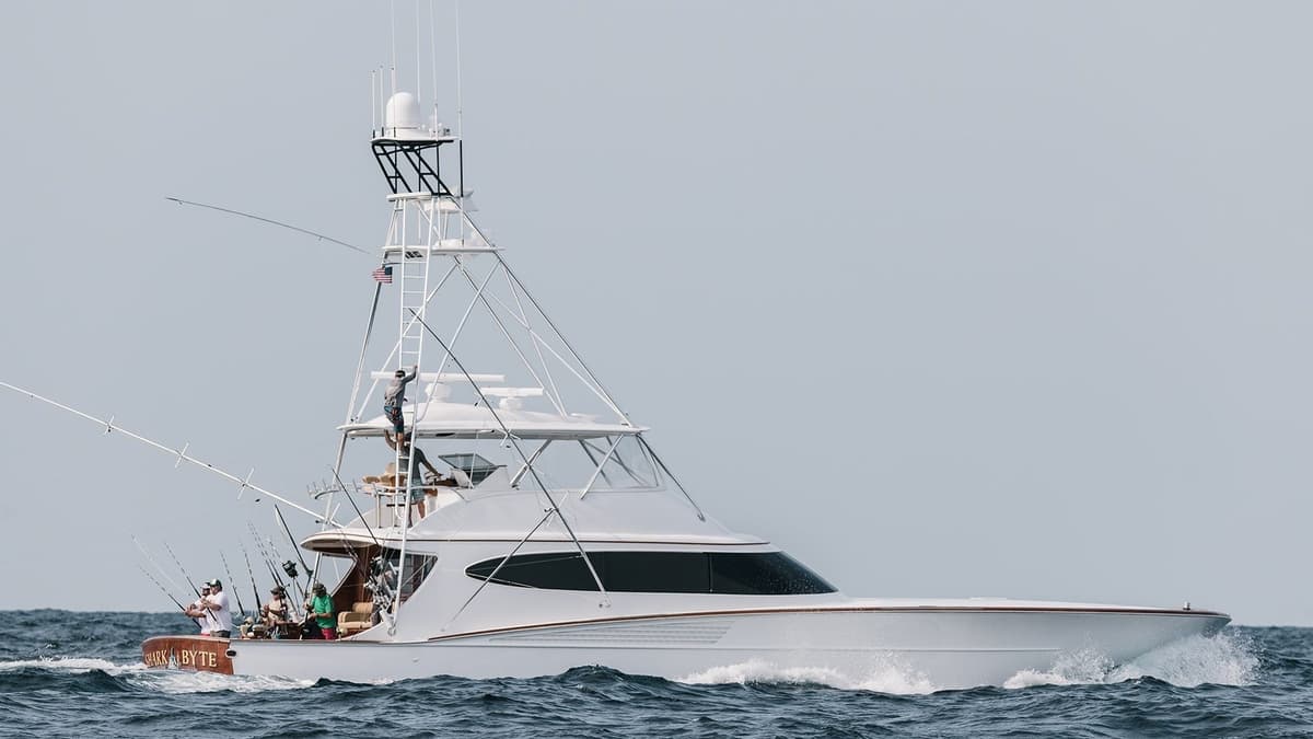 A modern sportfishing yacht with a sleek design cruising through the ocean, featuring multiple fishing rods and a large tower