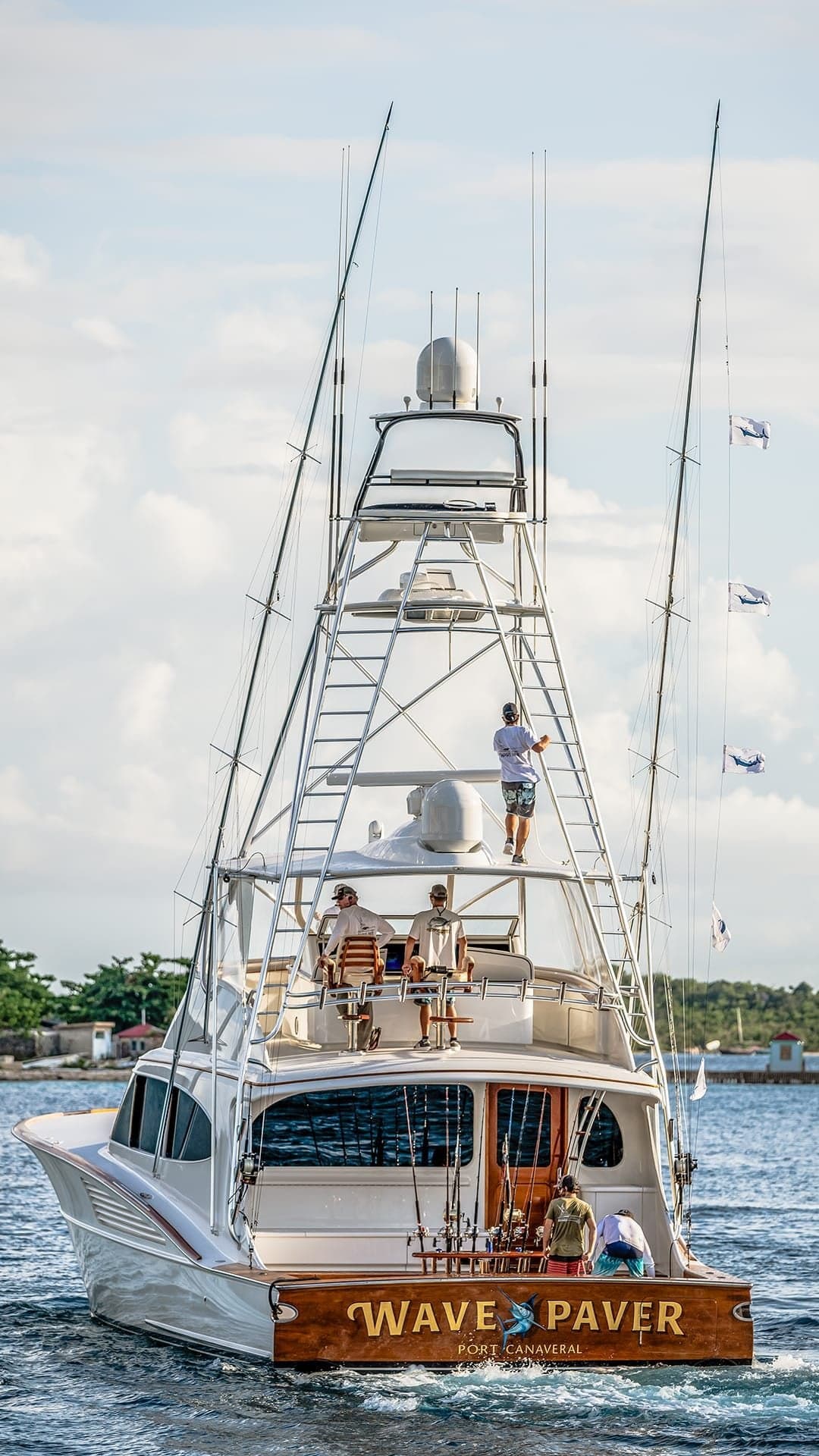 A sleek sportfishing yacht named Wave Paver, equipped with multiple antennas and fishing rods, navigates through open waters