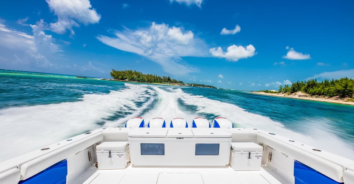 High-speed sportfishing boat cruising through clear blue waters surrounded by lush green islands