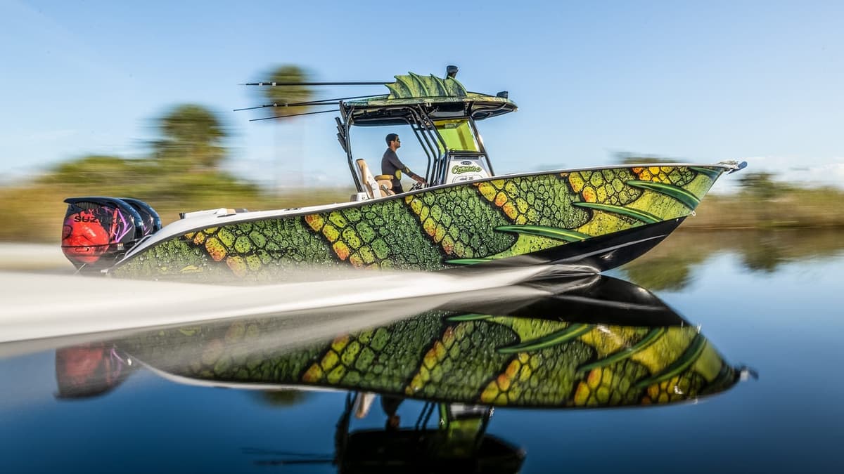 A vibrant sportfishing boat with a unique green and yellow patterned hull speeding across calm water