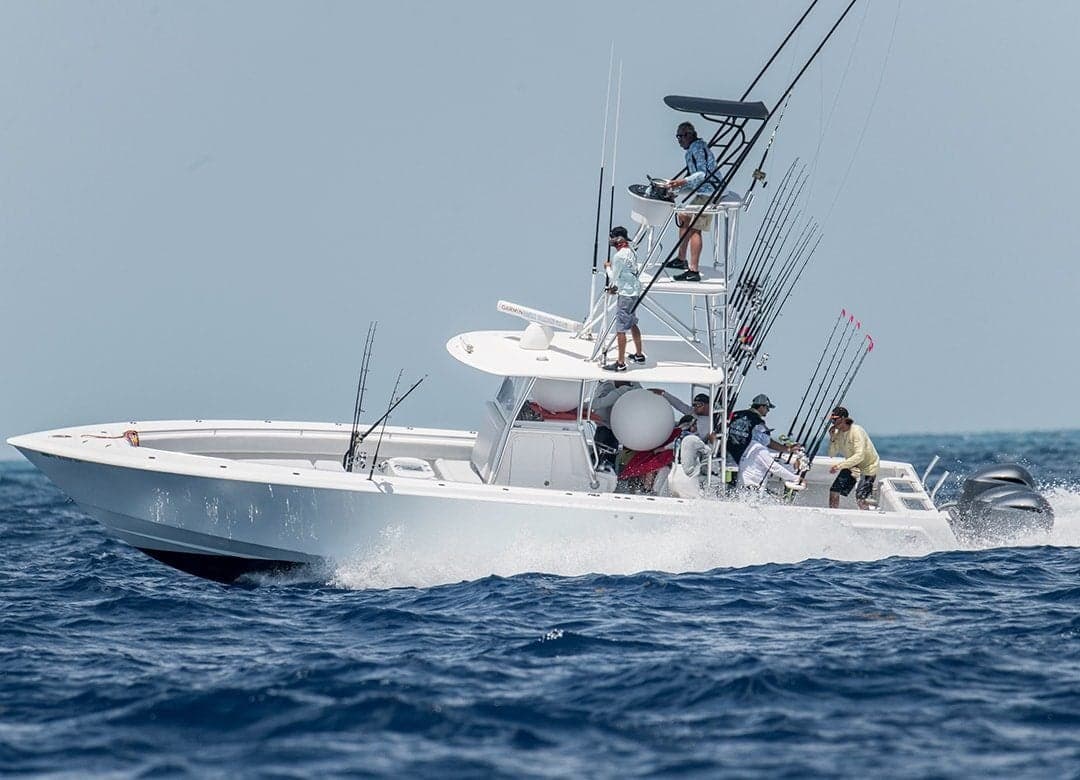 Sportfishing boat speeding through open water with multiple anglers and fishing rods on board