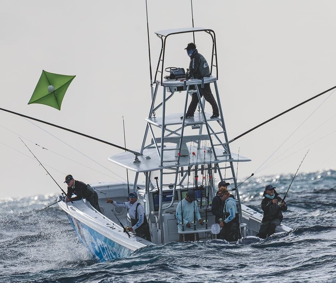 Group of anglers on a sportfishing boat battling waves and fishing lines in the water