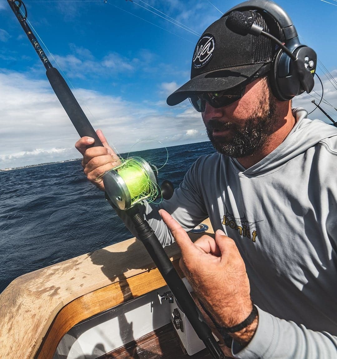 Fisherman wearing headphones untangling fishing line on a sportfishing boat in choppy waters