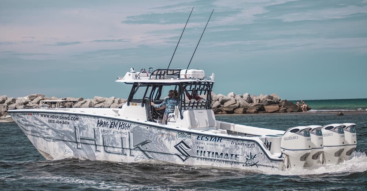A modern sportfishing boat with multiple outboard engines navigating through coastal waters