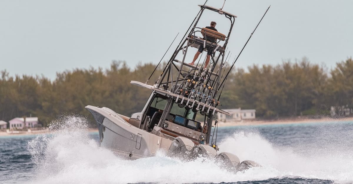 A powerful sportfishing boat surges through the water with multiple fishing rods and a watchful man on a high tower