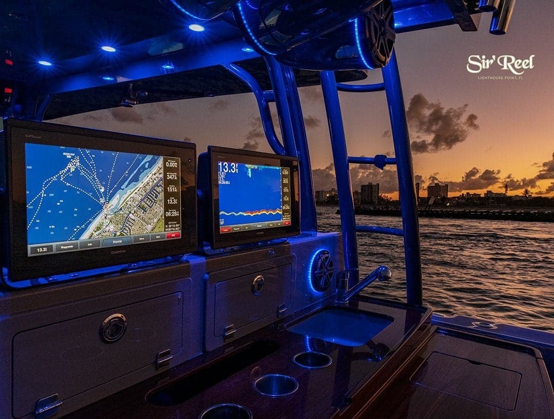 Interior of a modern fishing boat with illuminated navigation screens and a sunset over water