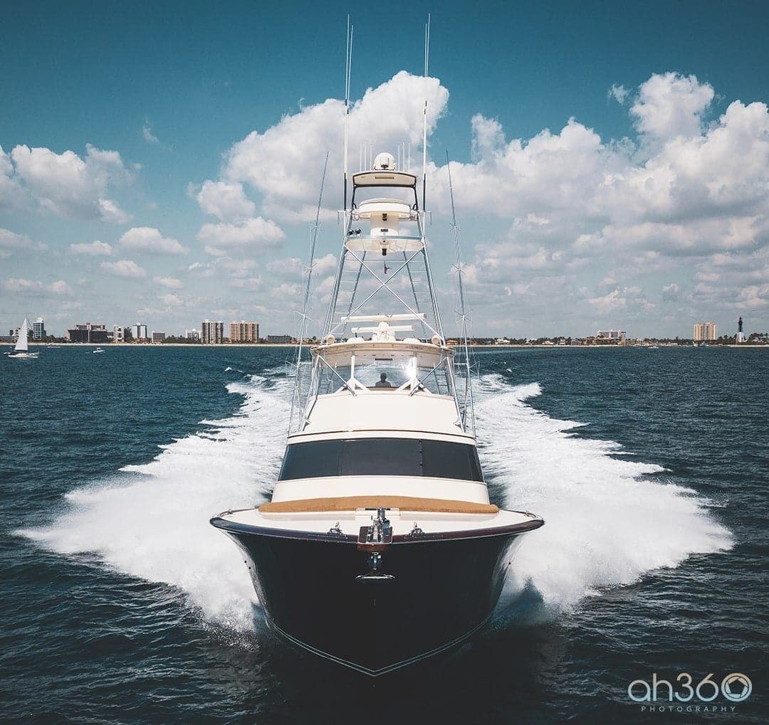 Front view of a sleek yacht speeding through open water under a partly cloudy sky