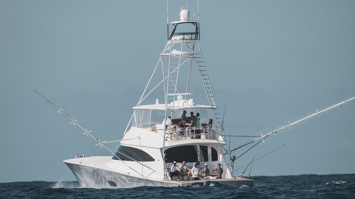 Large sportfishing yacht cruising through ocean waters, showcasing fishing rods and enthusiasts onboard