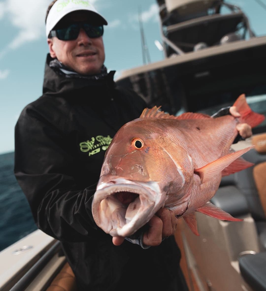 Angler holding a large, vibrant red fish on a sportfishing boat