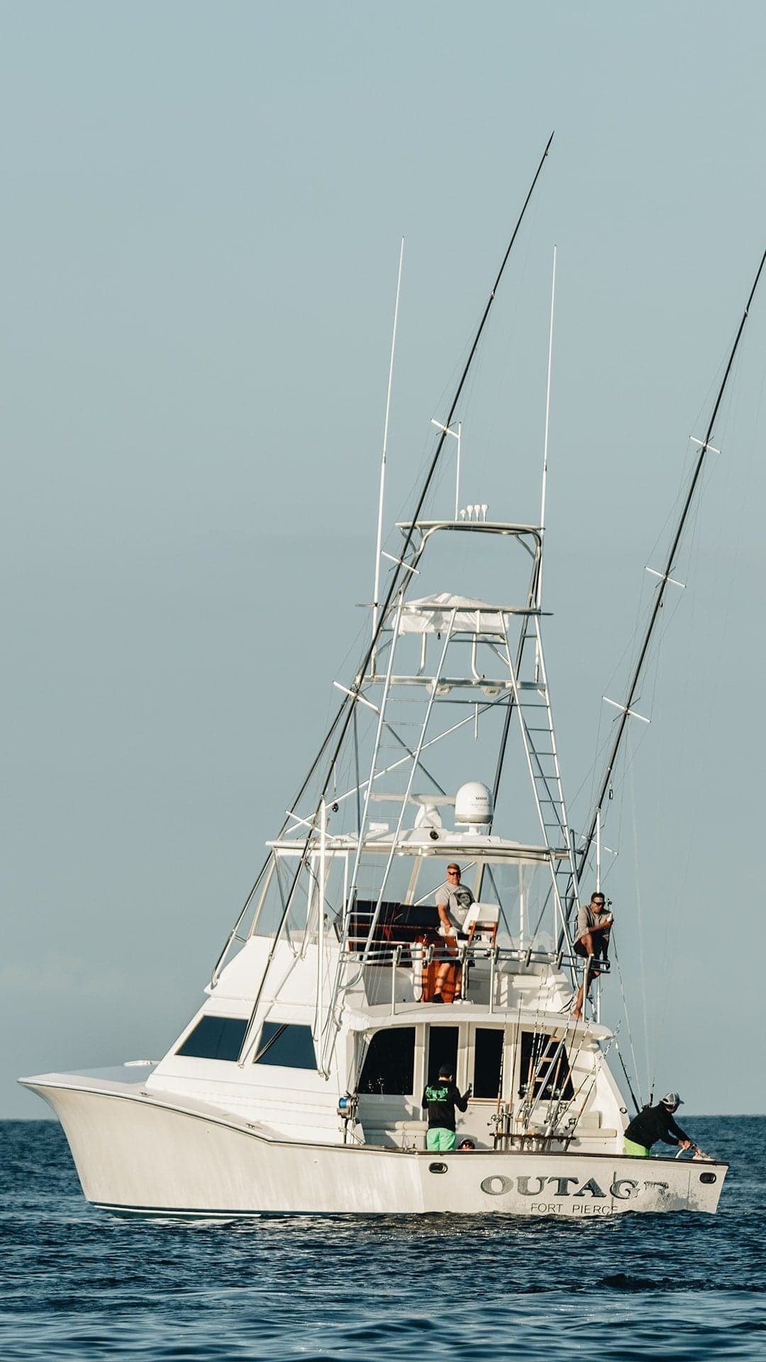 Sportfishing boat with anglers onboard, equipped for deep-sea fishing, featuring multiple fishing rods and a spacious deck