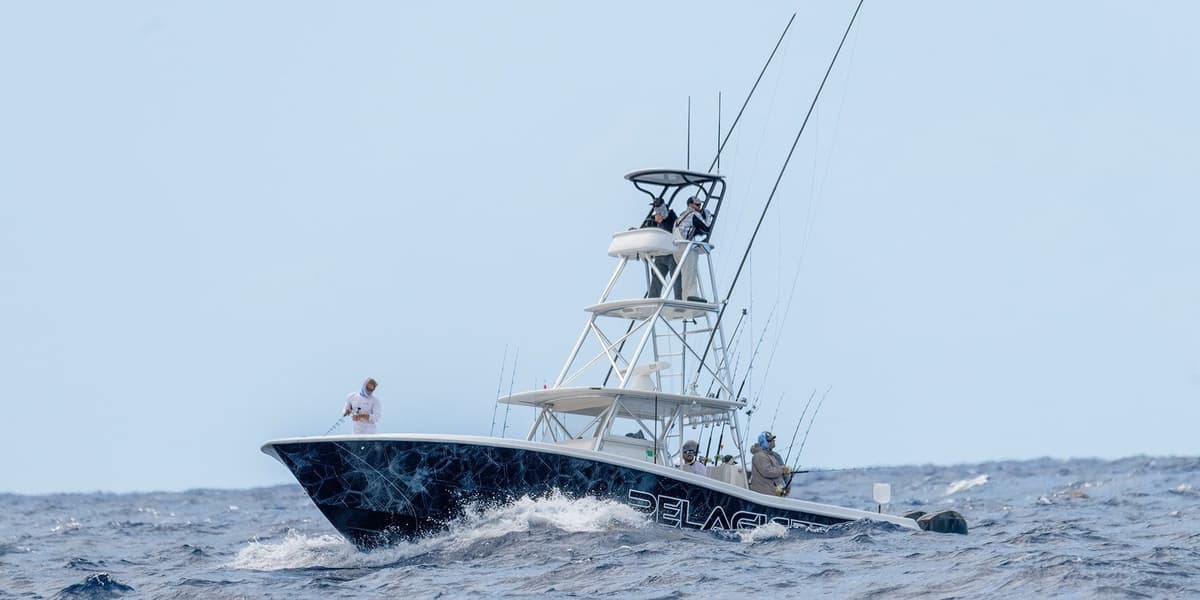 Sportfishing boat navigating ocean waves with multiple anglers onboard with fishing rods