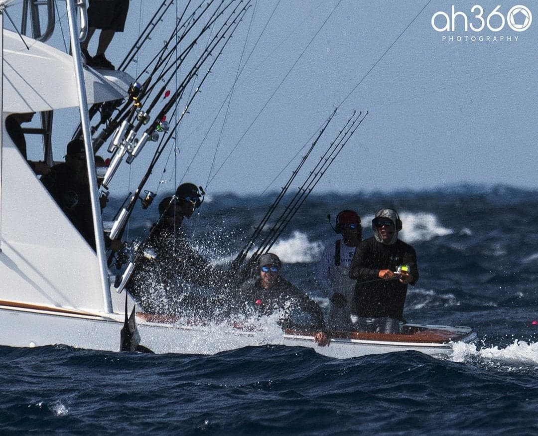 Group of anglers deep-sea fishing on a sportfishing boat surrounded by ocean waves with rods lined up
