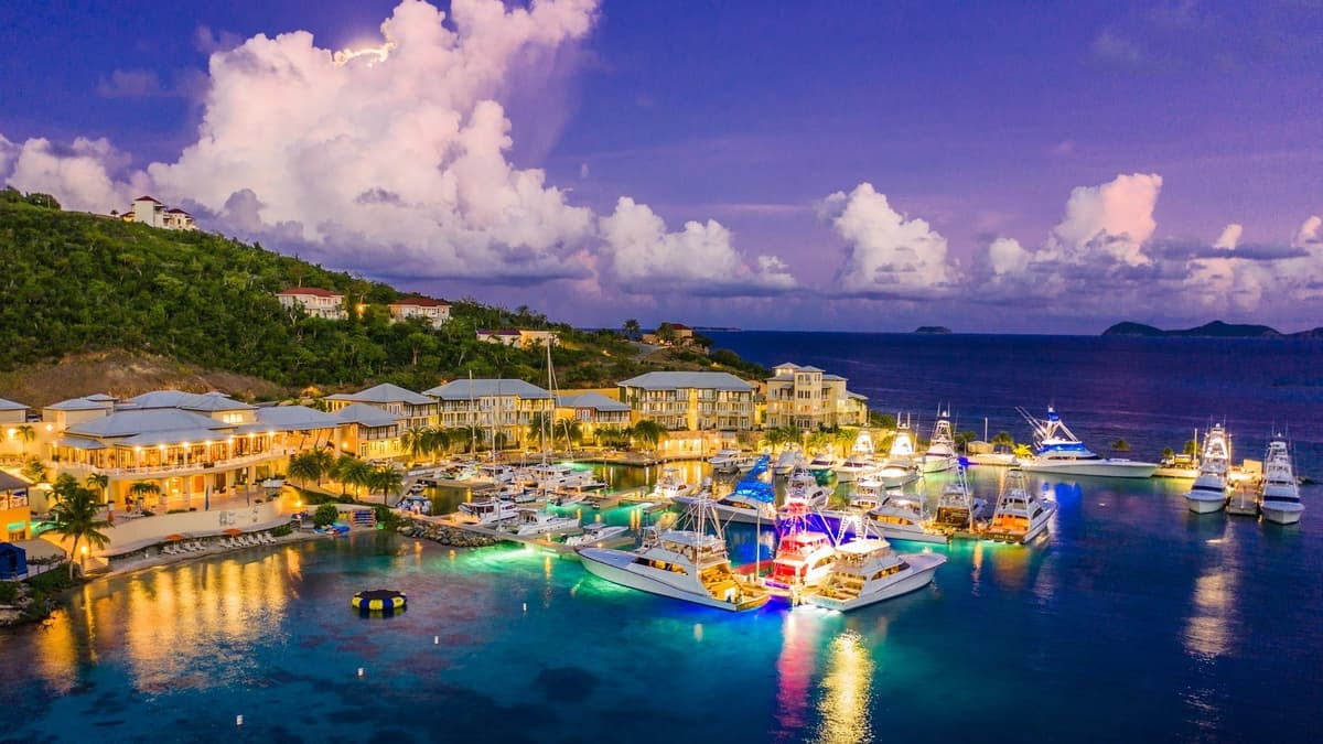 Aerial view of a brightly lit marina with sportfishing boats and yachts in tropical waters during twilight