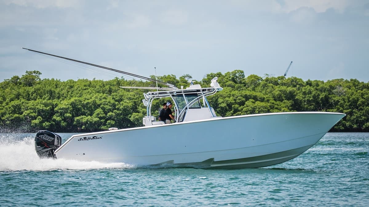 White sportfishing boat cruising rapidly on blue waters with lush greenery in the background