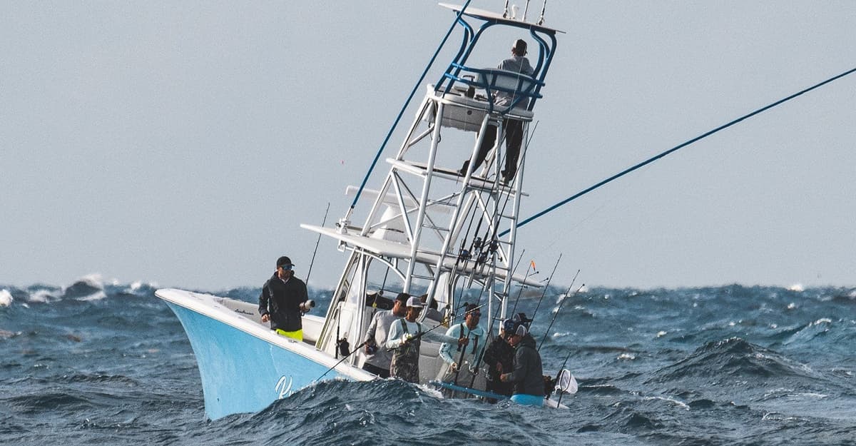 Sportfishing boat with anglers navigating rough seas with a blue hull and a prominent tower