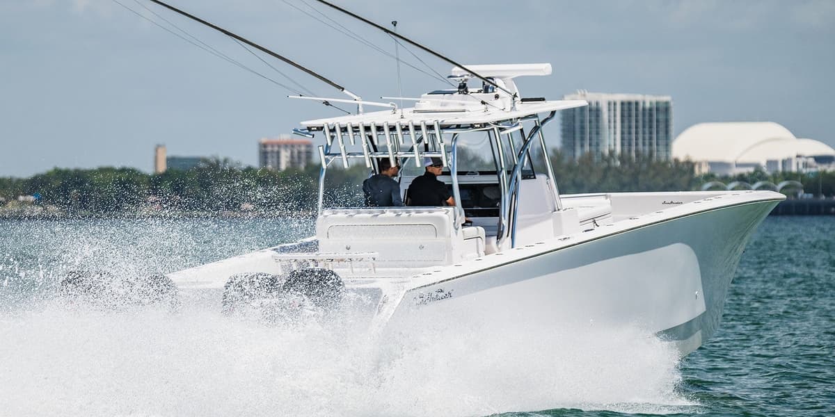 Dynamic photo of a sleek, white sportfishing boat speeding through the water with fishing rods ready