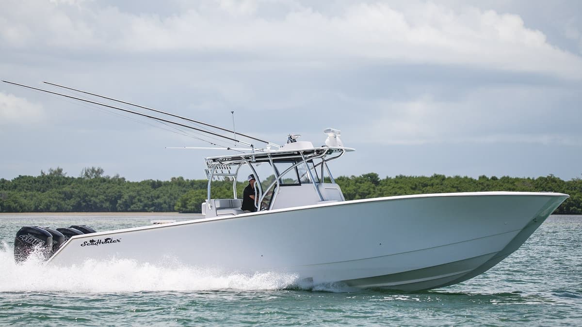 White sportfishing boat speeding across the water with greenery in the background