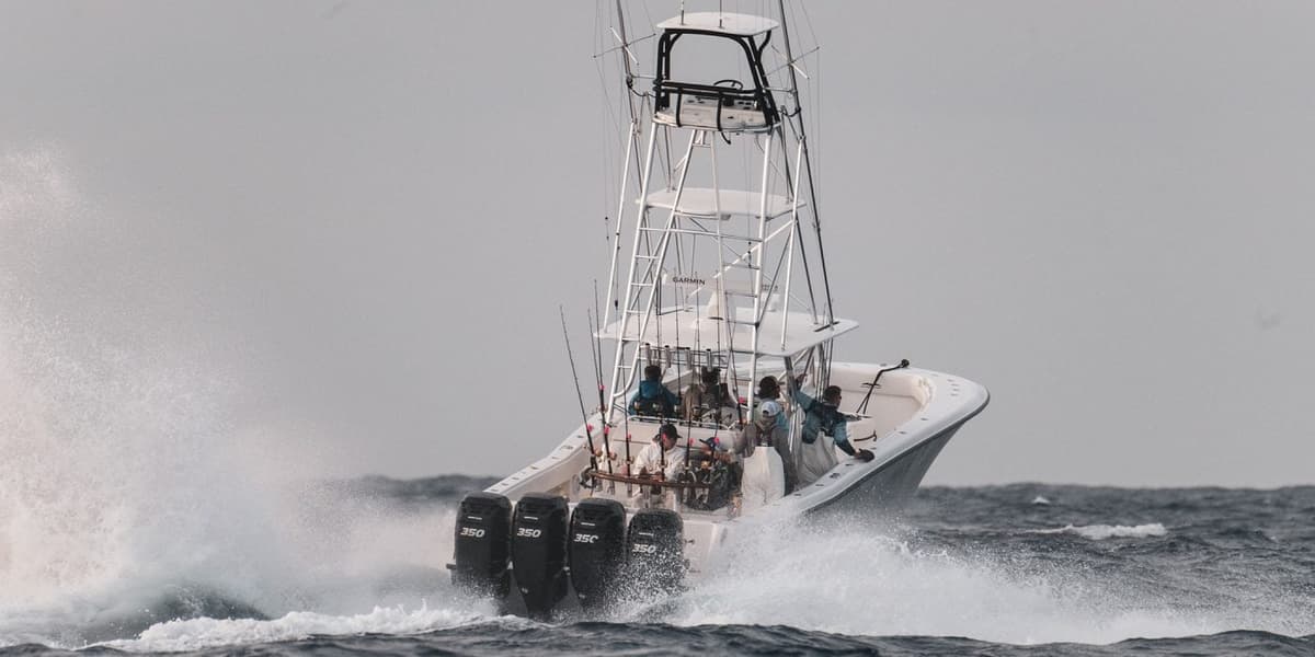 A sportfishing boat navigating through choppy waves with multiple passengers and fishing gear