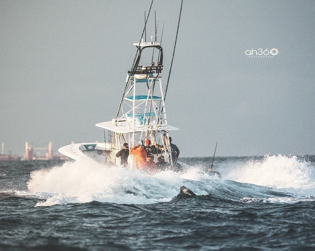 Sportfishing boat battling strong ocean waves with anglers on deck