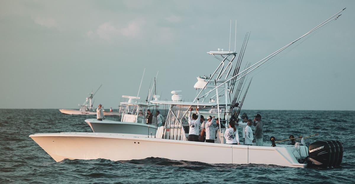 A fleet of sportfishing boats with anglers preparing their gear on a calm ocean