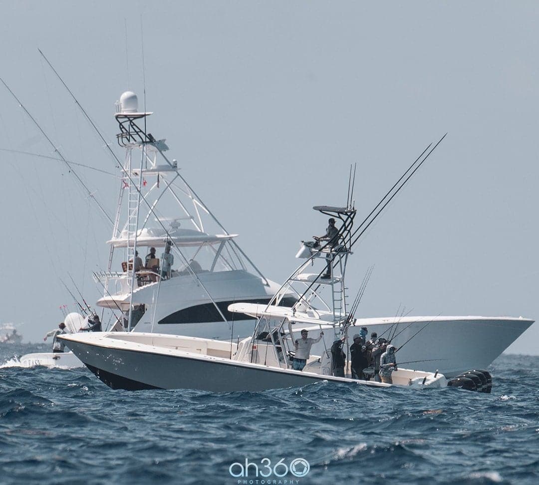 Two sportfishing boats navigating through waves with anglers on board and fishing rods equipped