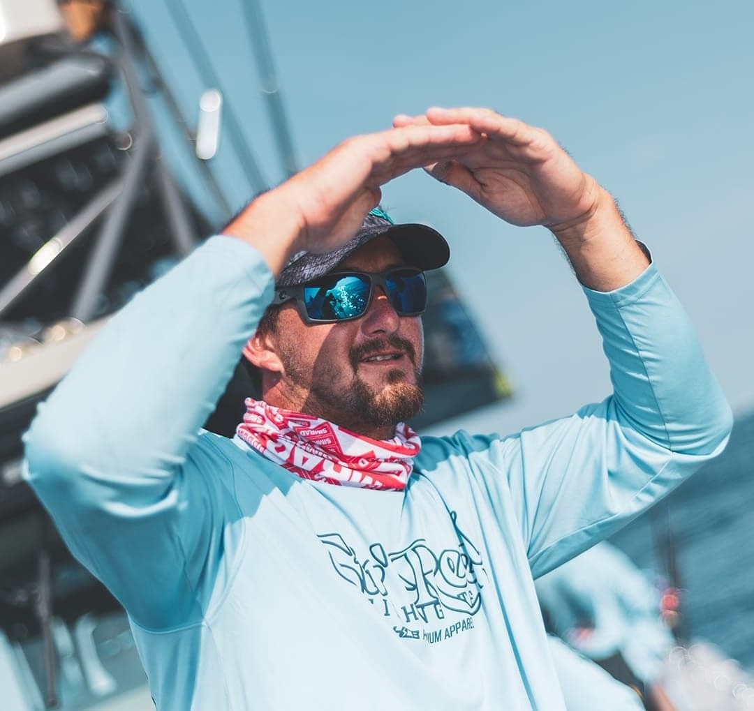 Man in blue shirt and sunglasses onboard a fishing boat during a sportfishing trip in South Florida