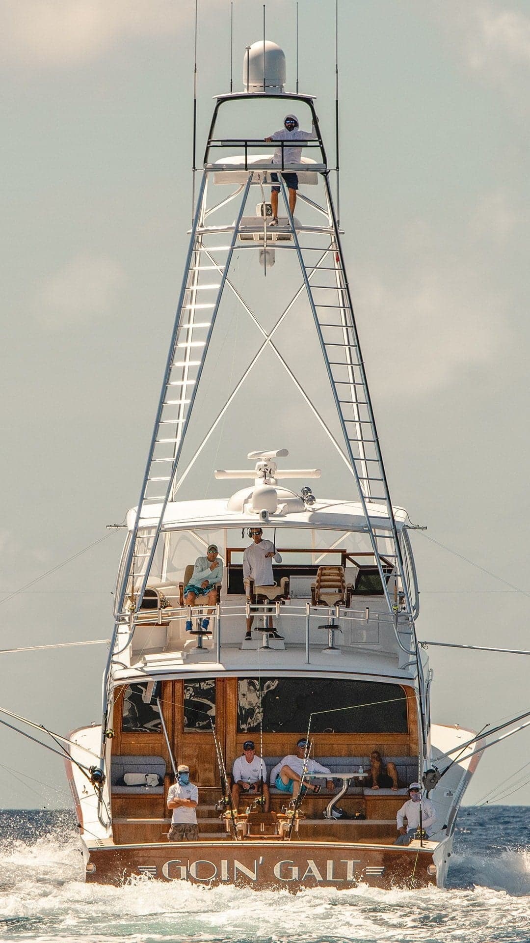 Front view of a sportfishing yacht named Goin Galt, featuring multiple decks and anglers aboard, cruising through open waters