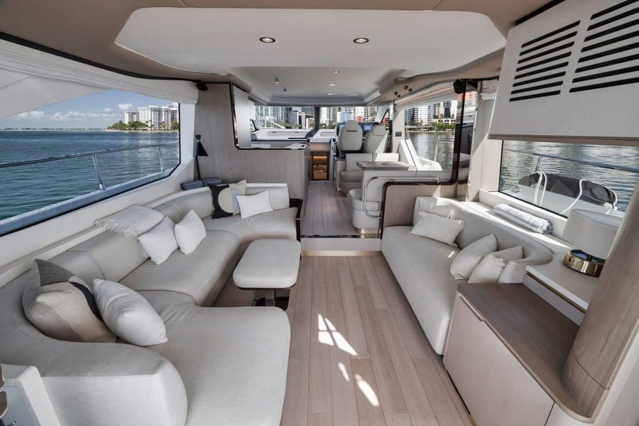 Motor yacht salon with the Miami waterfront visible through the windows, near Island Gardens Deep Harbour — charter marketing photography